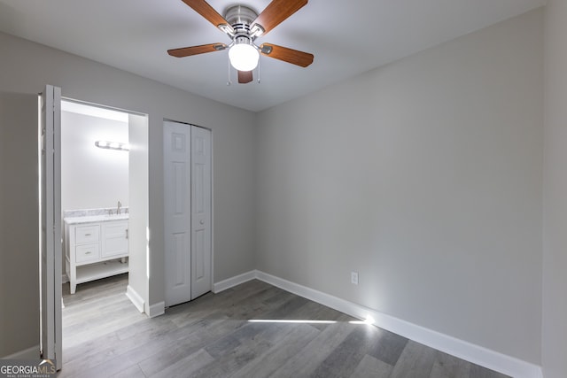 unfurnished bedroom with ceiling fan, light hardwood / wood-style floors, connected bathroom, and a closet