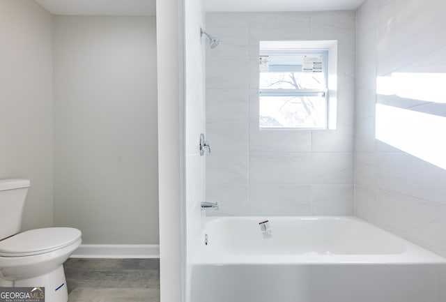 bathroom with tiled shower / bath combo and toilet