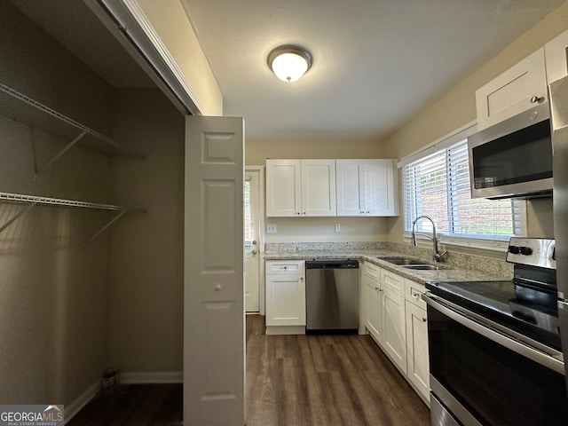 kitchen with light stone countertops, sink, stainless steel appliances, dark hardwood / wood-style floors, and white cabinets