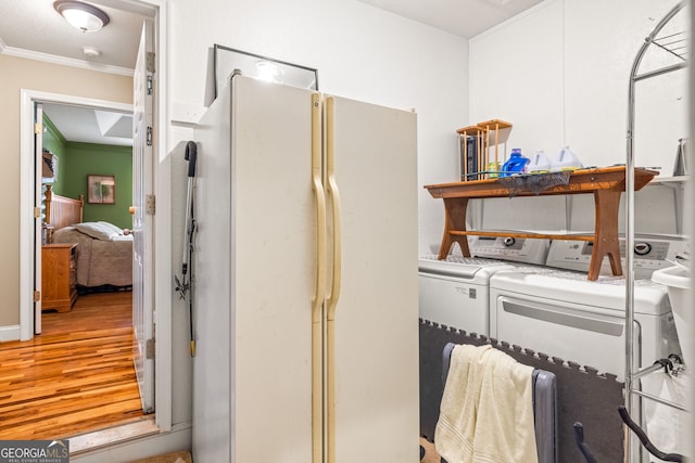 laundry area featuring laundry area, washer and dryer, wood finished floors, and ornamental molding