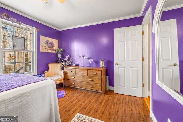 bedroom with baseboards, multiple windows, wood finished floors, and ornamental molding