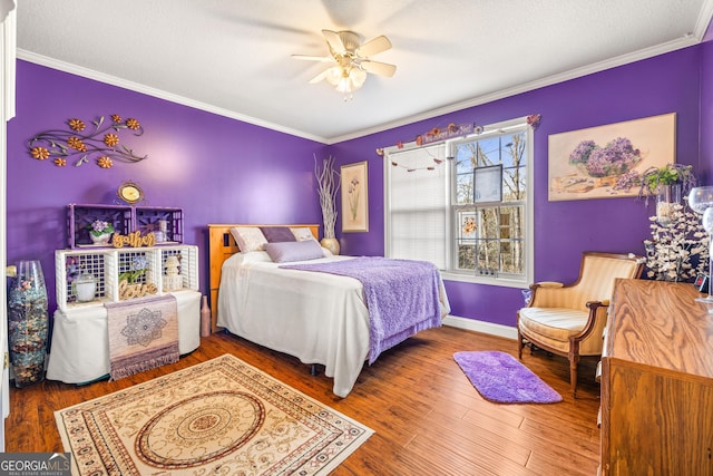 bedroom featuring ornamental molding, a textured ceiling, wood finished floors, baseboards, and ceiling fan