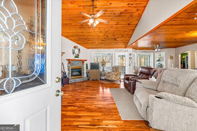 living room with ceiling fan, wood ceiling, a fireplace, wood finished floors, and arched walkways