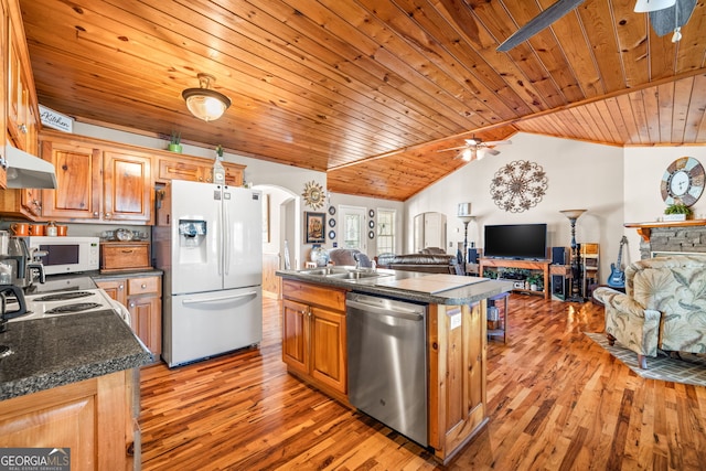 kitchen with a ceiling fan, a sink, dark countertops, arched walkways, and white appliances