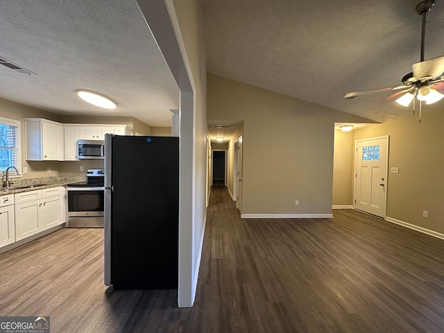 kitchen with white cabinets, wood-type flooring, a textured ceiling, and stainless steel appliances