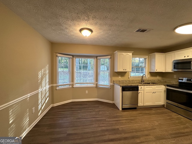 kitchen featuring light stone countertops, stainless steel appliances, sink, dark hardwood / wood-style floors, and white cabinetry