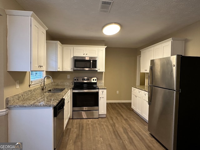 kitchen featuring white cabinetry, sink, stainless steel appliances, hardwood / wood-style floors, and a textured ceiling