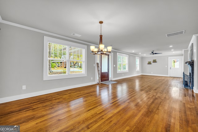 unfurnished living room with hardwood / wood-style floors, ceiling fan with notable chandelier, plenty of natural light, and crown molding