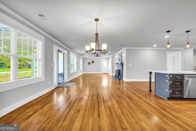 unfurnished living room with light hardwood / wood-style floors, crown molding, and a chandelier