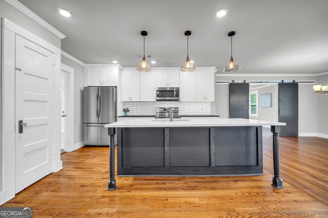 kitchen with white cabinets, a barn door, a breakfast bar area, and appliances with stainless steel finishes