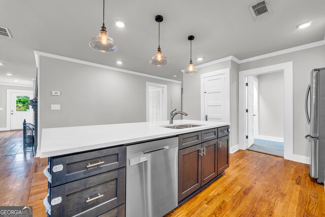 kitchen with stainless steel appliances, a kitchen island with sink, hanging light fixtures, and sink