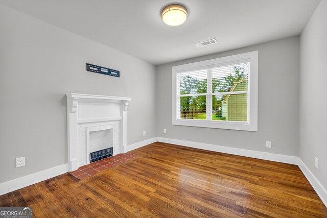 unfurnished living room with dark hardwood / wood-style floors and a tile fireplace