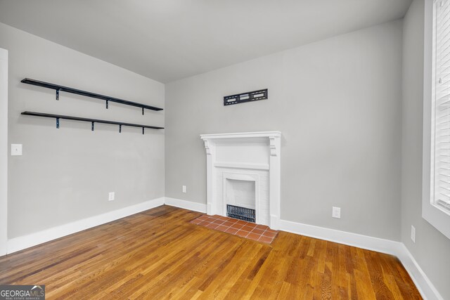 unfurnished living room with hardwood / wood-style floors and a brick fireplace