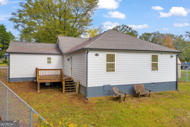 rear view of house featuring a deck and a lawn