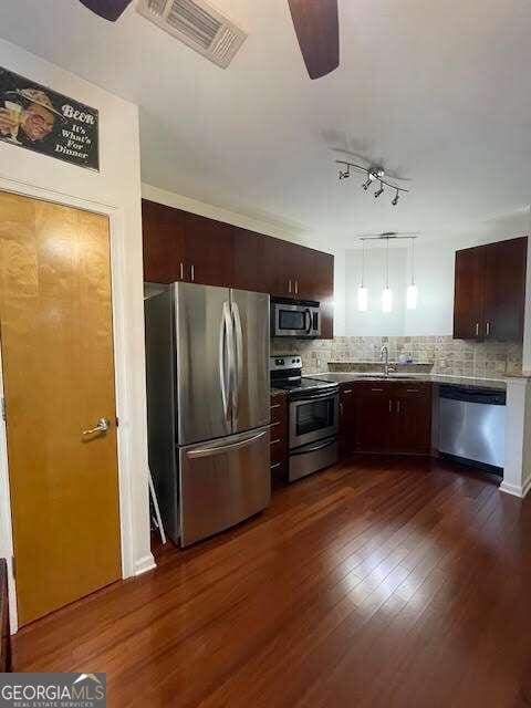 kitchen with sink, tasteful backsplash, dark hardwood / wood-style flooring, dark brown cabinets, and appliances with stainless steel finishes