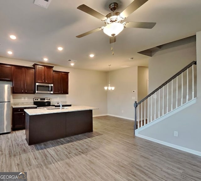 kitchen with a center island with sink, ceiling fan with notable chandelier, sink, light wood-type flooring, and appliances with stainless steel finishes