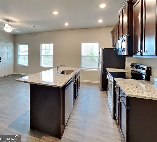 kitchen with appliances with stainless steel finishes, plenty of natural light, a kitchen island with sink, and sink