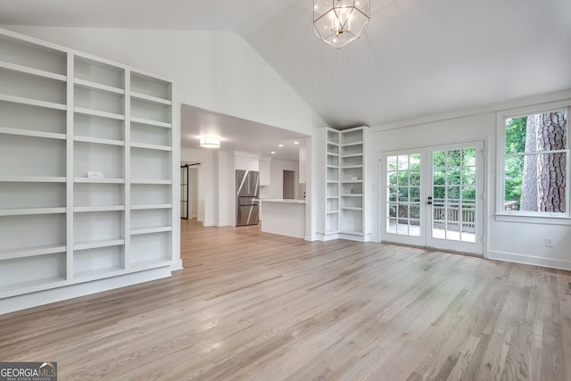 unfurnished living room featuring french doors, high vaulted ceiling, light hardwood / wood-style floors, and an inviting chandelier