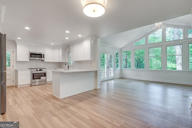 kitchen featuring sink, light hardwood / wood-style flooring, kitchen peninsula, white cabinets, and appliances with stainless steel finishes