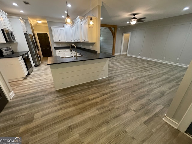 kitchen featuring white cabinets, decorative light fixtures, kitchen peninsula, and appliances with stainless steel finishes