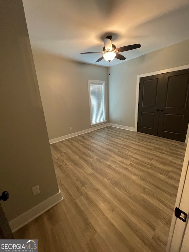 unfurnished bedroom featuring wood-type flooring, a closet, and ceiling fan