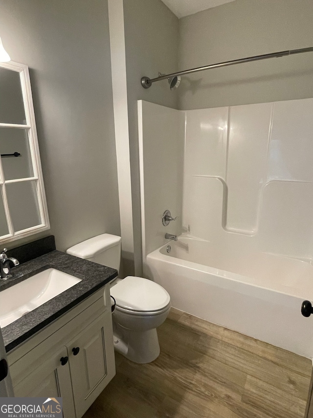 full bathroom featuring hardwood / wood-style floors, vanity, toilet, and washtub / shower combination