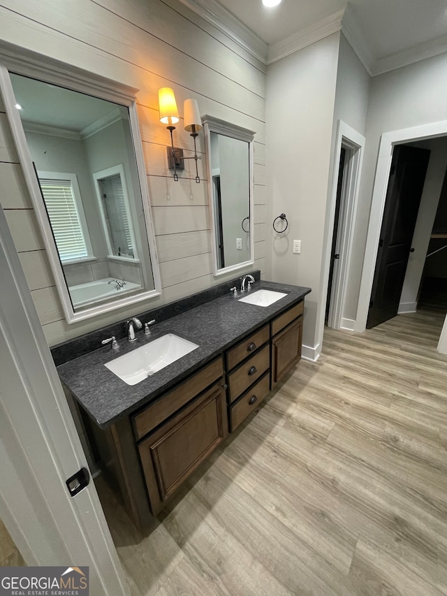 bathroom with a bathing tub, wood-type flooring, vanity, and crown molding