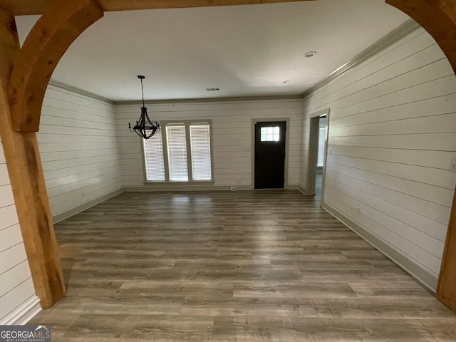 foyer entrance with hardwood / wood-style floors and wood walls