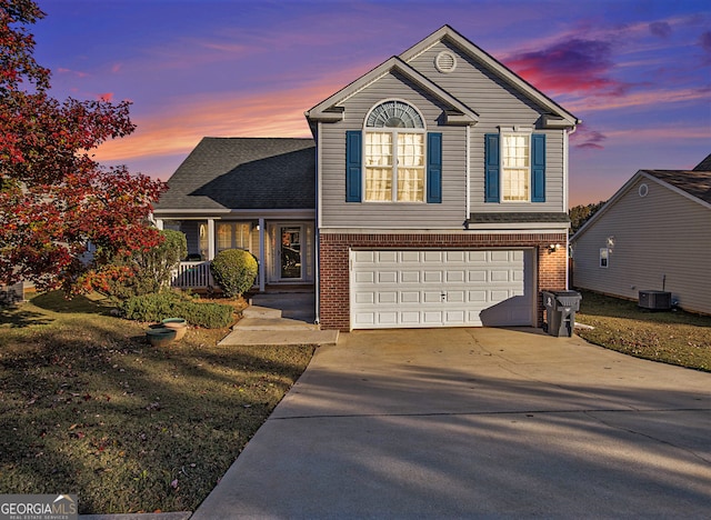 view of front of home featuring a garage, a yard, and central AC