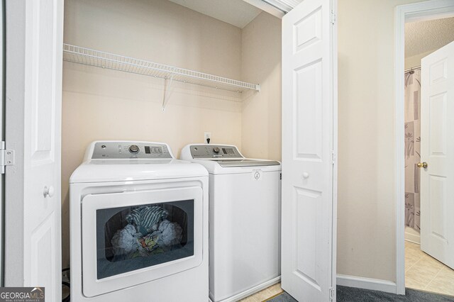 clothes washing area with a textured ceiling, separate washer and dryer, and light tile patterned flooring