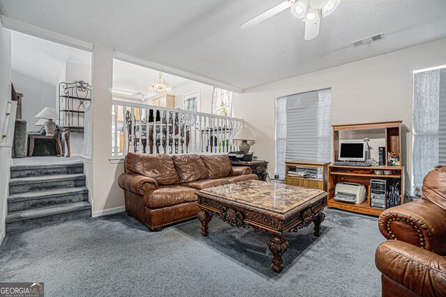 carpeted living room with ceiling fan with notable chandelier and a textured ceiling