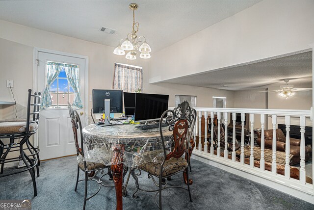 carpeted dining space featuring ceiling fan with notable chandelier and a textured ceiling