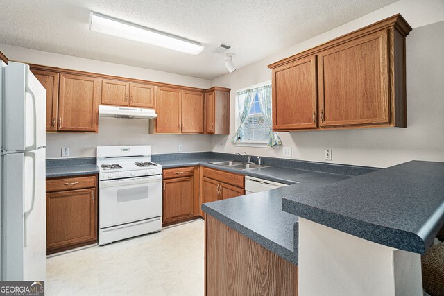 kitchen with a textured ceiling, kitchen peninsula, white appliances, and sink