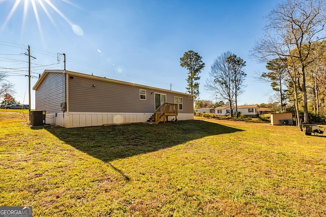 rear view of property featuring central air condition unit, a lawn, and a storage unit