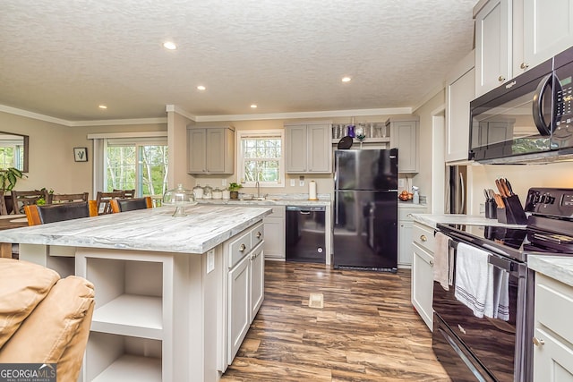 kitchen with black appliances, a kitchen island, a healthy amount of sunlight, and a textured ceiling