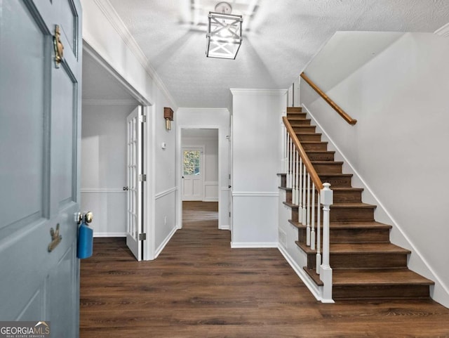 foyer featuring a textured ceiling, crown molding, and dark wood-type flooring