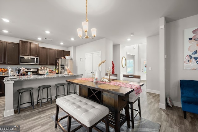 kitchen featuring an island with sink, appliances with stainless steel finishes, pendant lighting, and a breakfast bar area