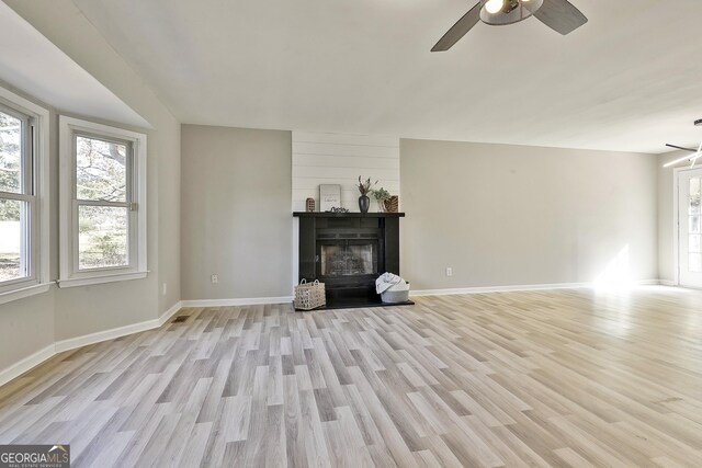 unfurnished living room featuring ceiling fan, light hardwood / wood-style floors, and a fireplace