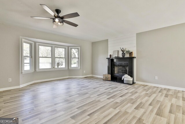 unfurnished living room featuring a fireplace, light wood-type flooring, and ceiling fan