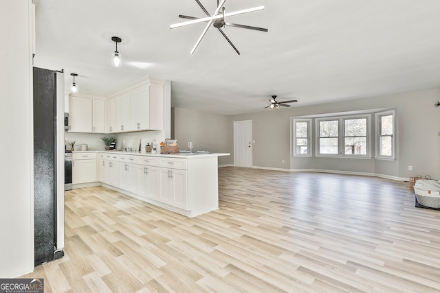 kitchen featuring kitchen peninsula, ceiling fan, pendant lighting, light hardwood / wood-style flooring, and white cabinetry