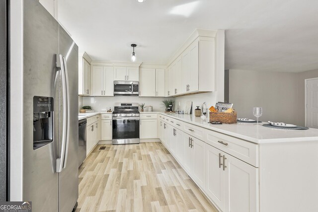 kitchen featuring kitchen peninsula, appliances with stainless steel finishes, pendant lighting, light hardwood / wood-style floors, and white cabinetry