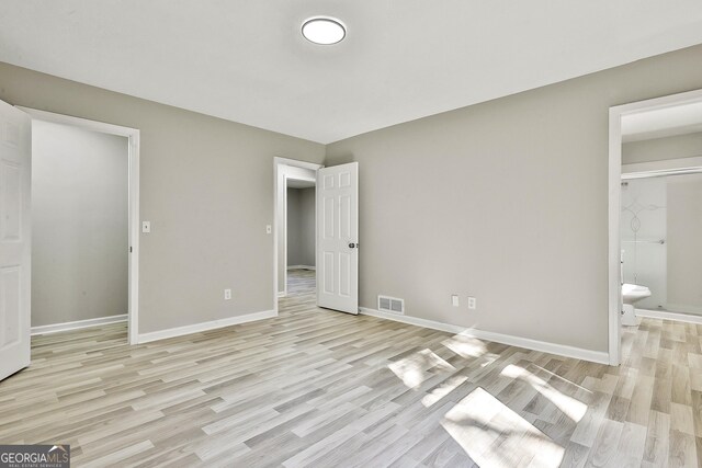 unfurnished bedroom featuring light hardwood / wood-style floors and ensuite bath