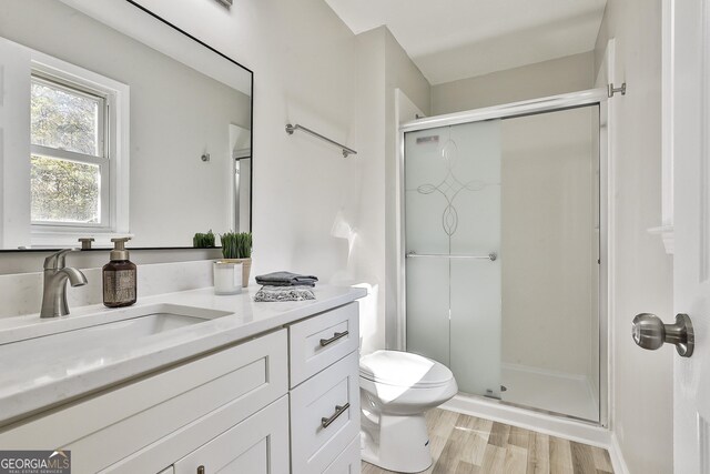 bathroom featuring hardwood / wood-style flooring, vanity, toilet, and walk in shower