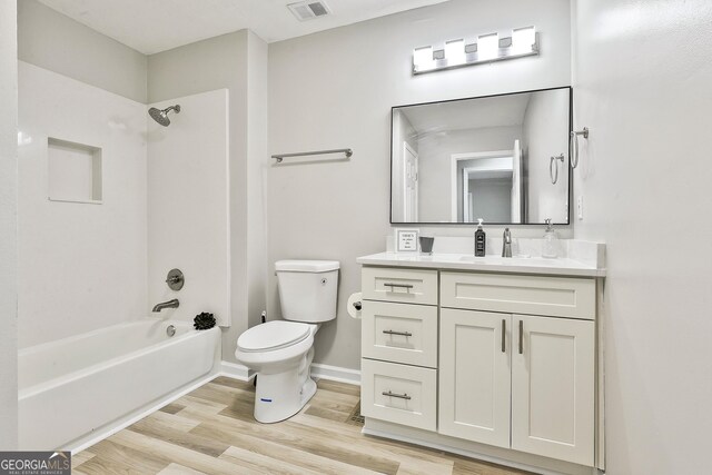 full bathroom featuring washtub / shower combination, vanity, hardwood / wood-style flooring, and toilet