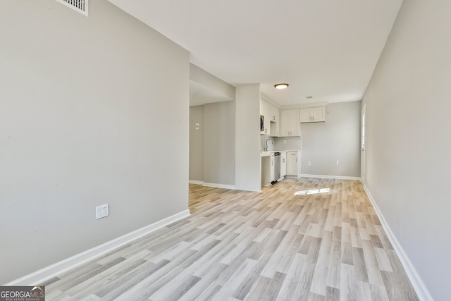 unfurnished living room featuring light wood-type flooring and sink