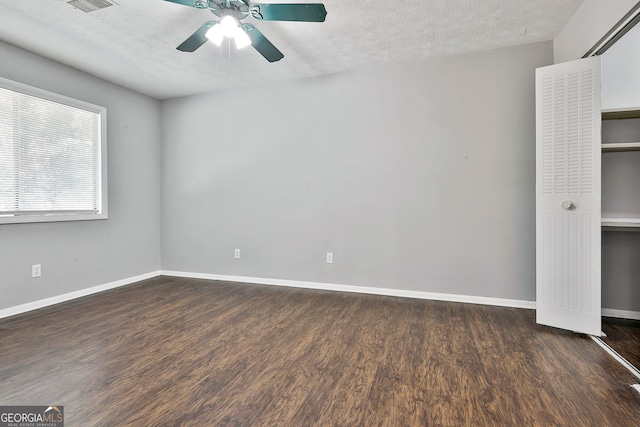 unfurnished bedroom featuring ceiling fan, dark wood-type flooring, and a textured ceiling