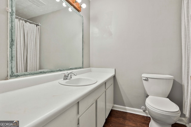 bathroom featuring vanity, wood-type flooring, a textured ceiling, and toilet