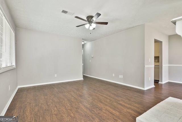 empty room with a textured ceiling, ceiling fan, and dark hardwood / wood-style floors