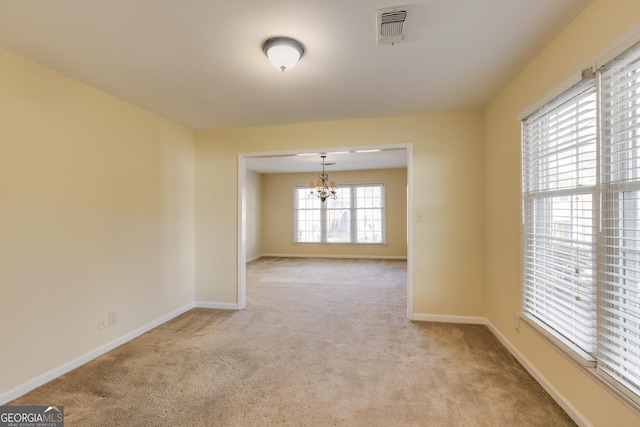 spare room with visible vents, baseboards, light carpet, and an inviting chandelier