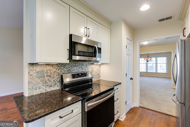 kitchen with tasteful backsplash, a chandelier, hardwood / wood-style floors, and stainless steel appliances